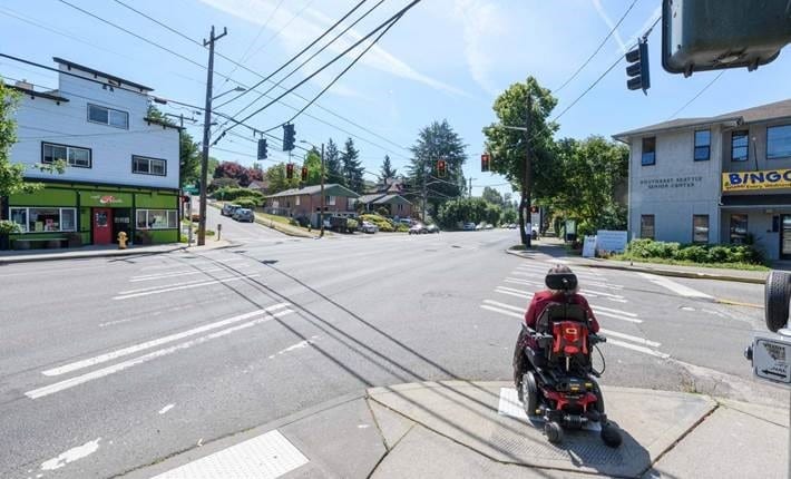 Person in motorized wheelchair waiting to cross the street.