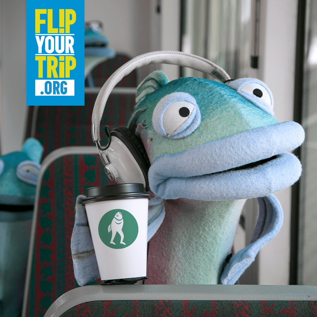 Sal the Salmon wearing earphones and holding a coffee cup while sitting on the Seattle Streetcar.