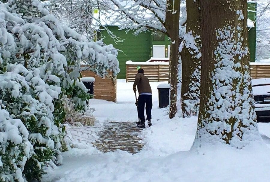 Man shoveling snow on the sidewalk.