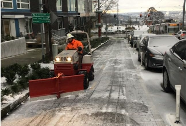 Mini snow plow working to clear protected bike lanes