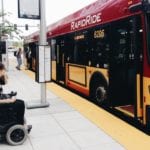 Pedestrian in electric wheelchair waiting to get on the Rapid Line C.