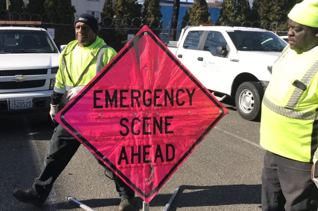 SRT members Anthony Monroe and Marcus Potts standing near a pink Emergency Scene Ahead sign. 