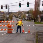 An SDOT crew member placing street closed signs and traffic cones.