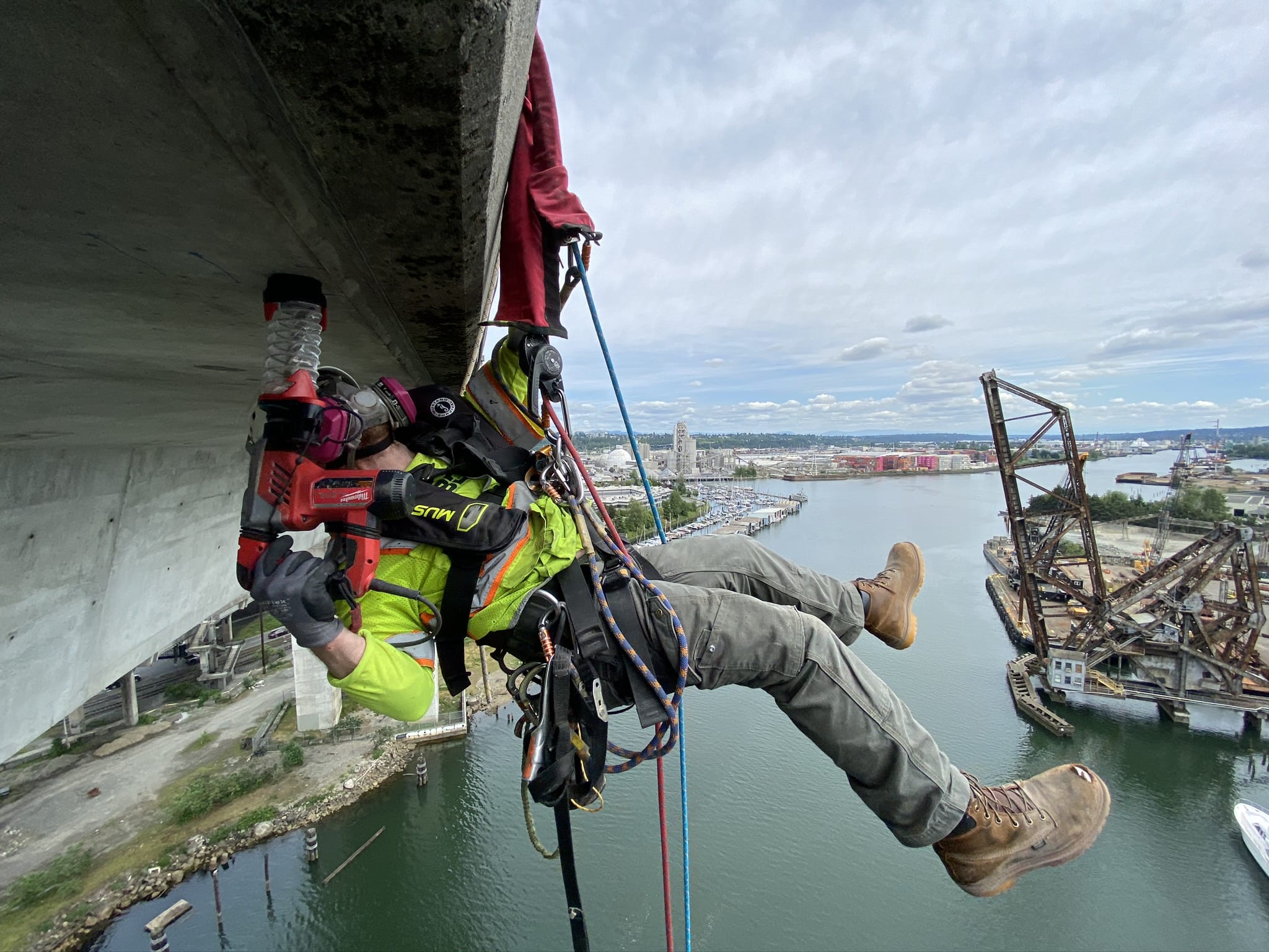 Crew member suspended by ropes and safety harnesses descended from the edge of the West Seattle High-Rise bridge to drill precision holes in the concrete and collect core samples.