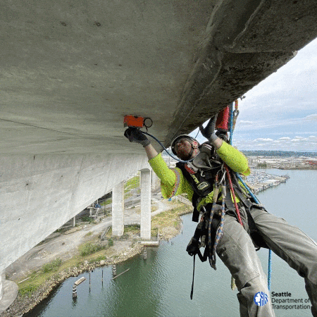 Crew suspended by ropes, drilling into the West Seattle Bridge to collect samples of the concrete to test for corrosion.