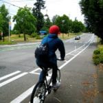 A person riding a bike down a protected bike lane.