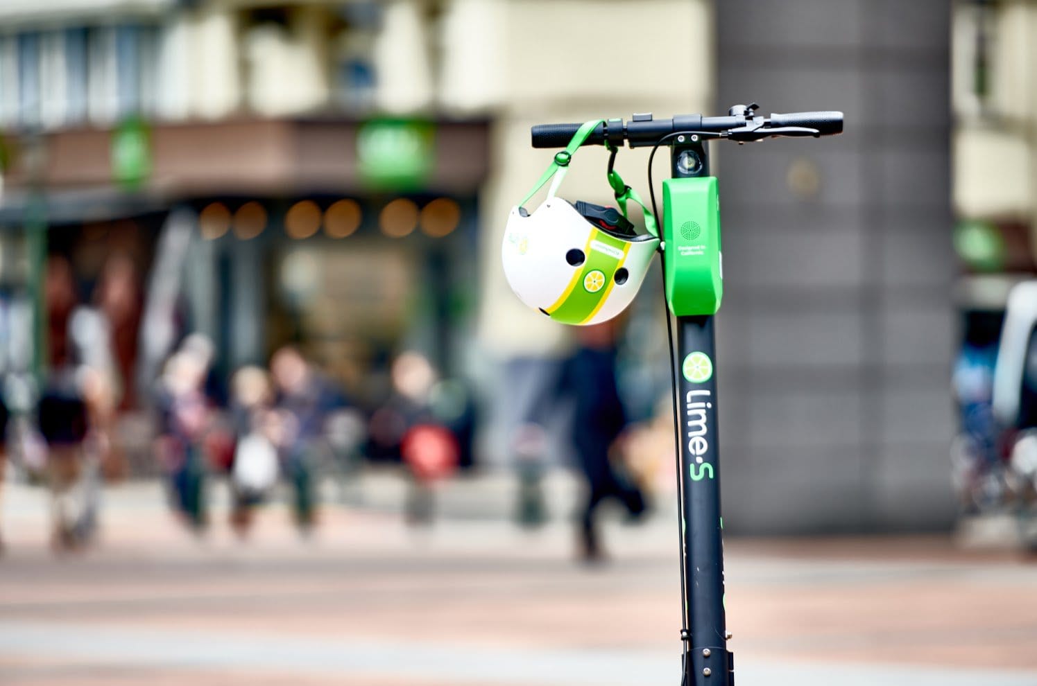 Lime scooter on a city street, with a blurred background of people and businesses.