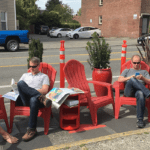 Seattle residents relaxing in red chairs in a parking space usually reserved for cars. Photo Credit: SDOT Flickr