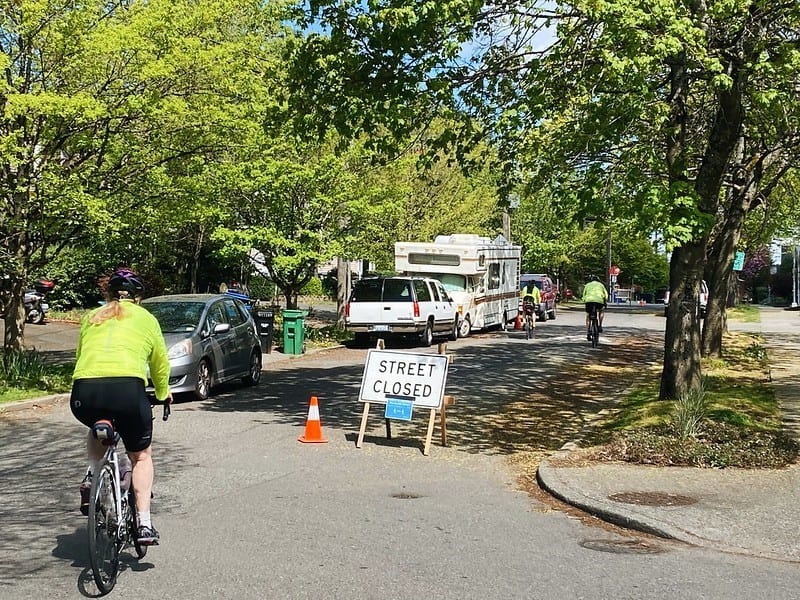 People biking on a Stay Healthy Street in Seattle. Street Closed sign is visible.