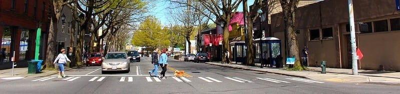 Panoramic photo of people crossing the street at the intersection of Rainier Ave S and S Orcas St in Hillman City.