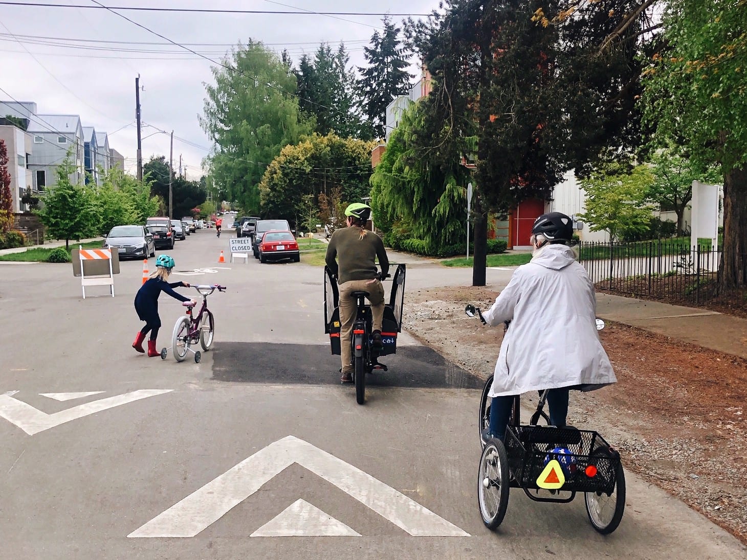 People biking on a Stay healthy Street in Seattle over a speed bump.