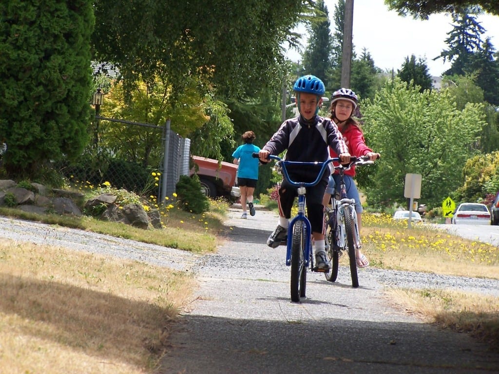 Young children biking on a sidewalk in West Seattle.