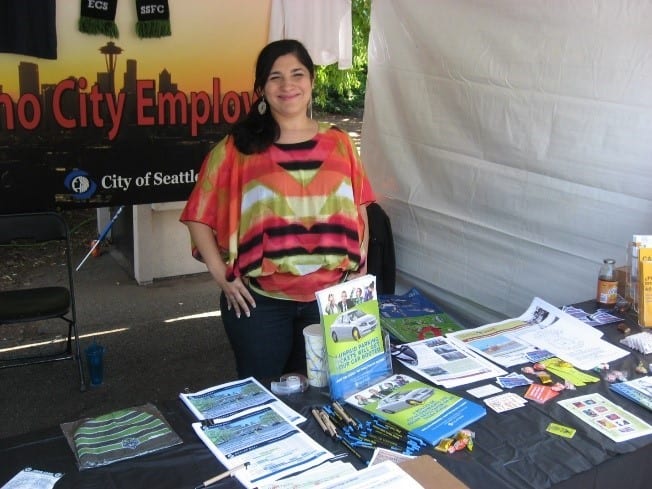 Sonia standing behind a table of materials at a community outreach event.