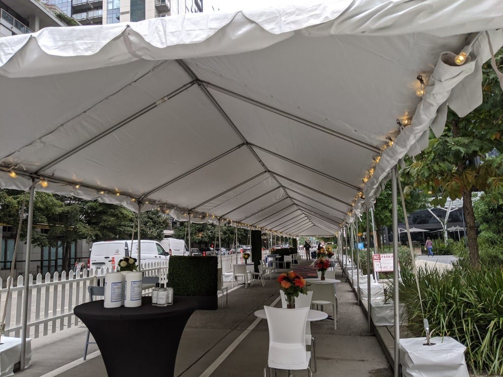 Covered dining space. Tables are shown under large white tent.