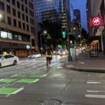 Someone riding the 4th Ave protected bike lane at night.