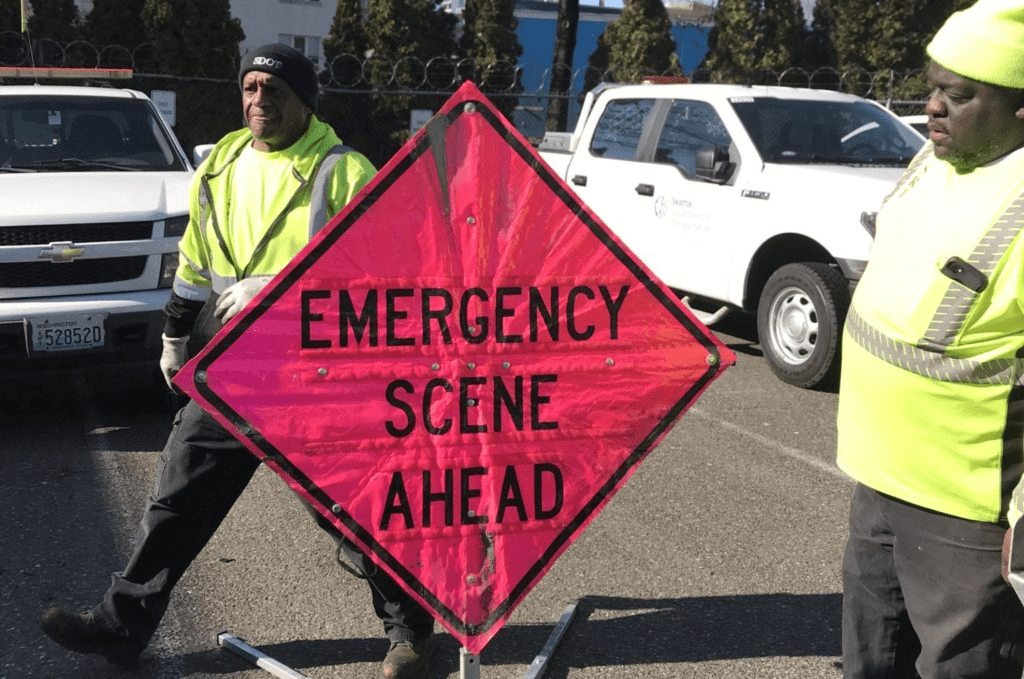 Two SRT members standing near a pink Emergency Scene Ahead sign. 