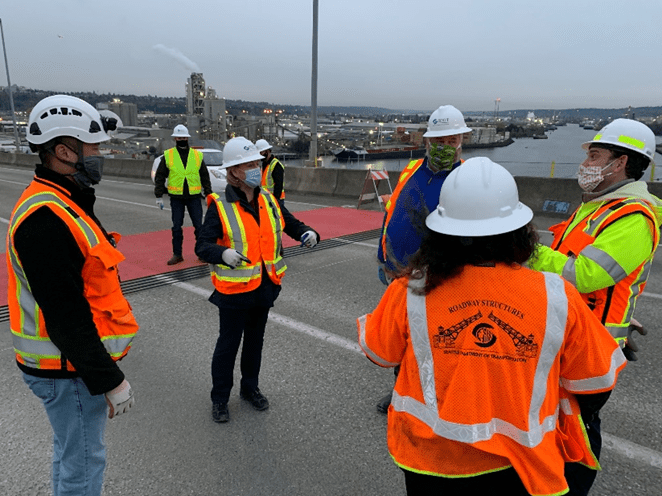 Mayor Jenny Durkan, SDOT Director Sam Zimbabwe, CTF co-chairs Paulina Lopez and Greg Nickels, and SDOT engineer Kit Loo stand on the West Seattle Bridge and discuss.