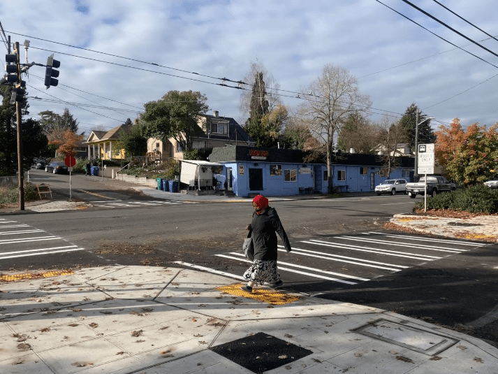 A person crossing the street on a new crosswalk, and walking up a curb ramp. 