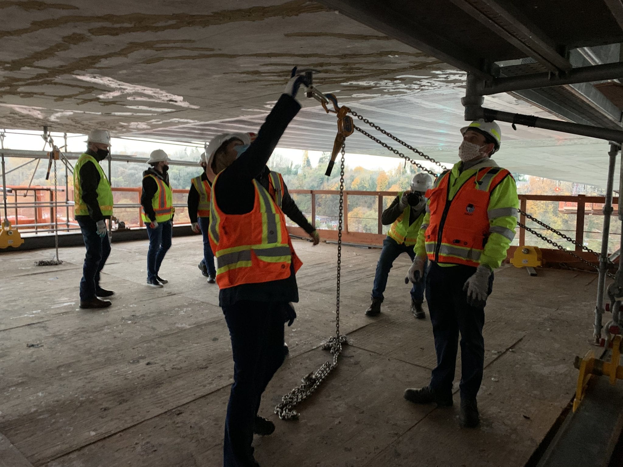 Crews stand with SDOT Director Sam Zimbabwe on the work platforms suspended under the West Seattle High-Rise Bridge.