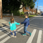 Two children crossing the street holding hands.