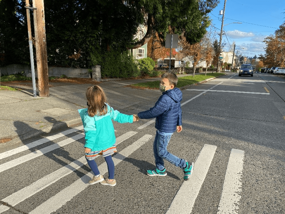 Two children crossing the street holding hands.