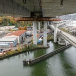 The West Seattle High Rise Bridge work platforms suspended under the bridge. The platforms are mostly orange. The Duwamish waterway can be seen below the platforms.