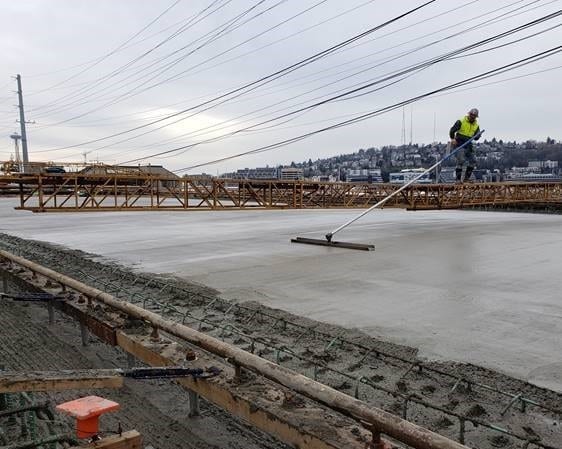 Crews smoothing out concrete over the bridge deck. 