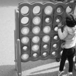 Black and white photo of kid playing giant Connect Four game
