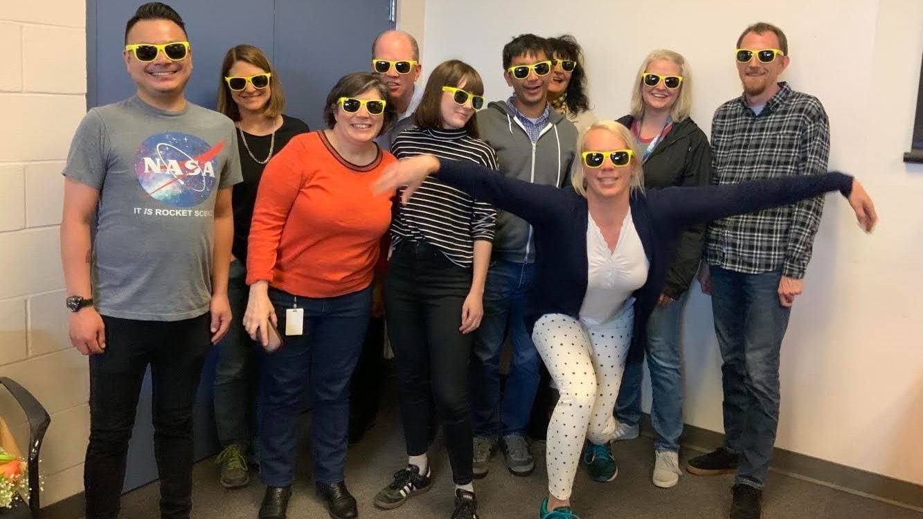 10 people posed with matching yellow sunglasses