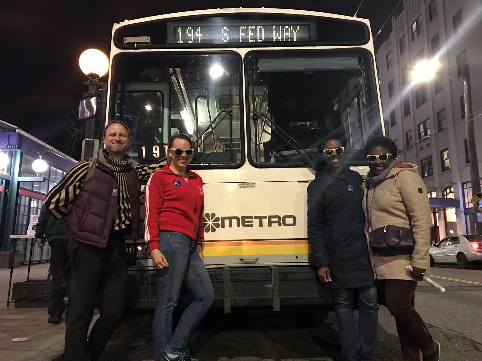 Four people standing in front of retro Metro bus