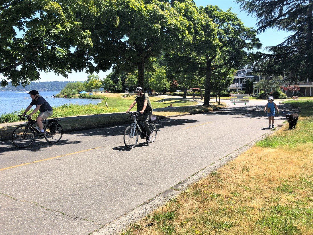 People biking and walking a dog on the Lake Washington Blvd Stay Healthy Street.