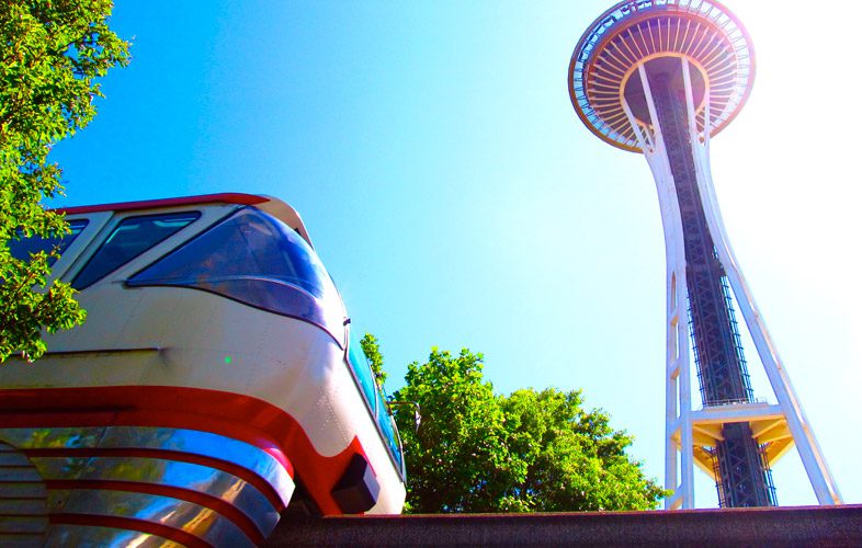Image showcasing the Seattle Center Monorail and the Space Needle, on a sunny day. Photo credit: Megan Ching - Seattle Monorail Services.