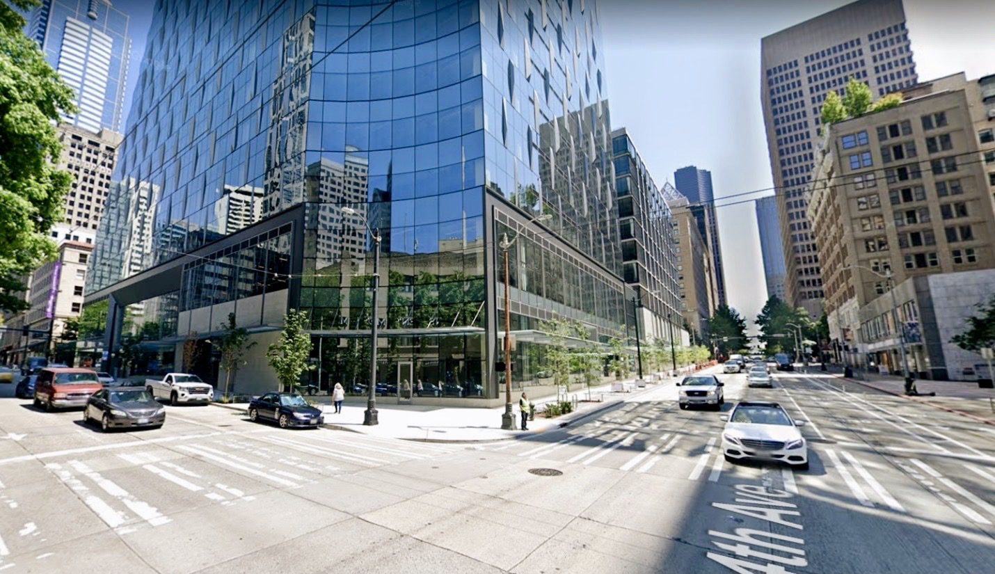 The intersection of 4th Ave and Union St is visible with large buildings such as the new Rainier Square Tower visible in the center and upper right side of the image. Cars are visible on the right driving down 4th Ave, with additional vehicles queued up on Union St to the left.