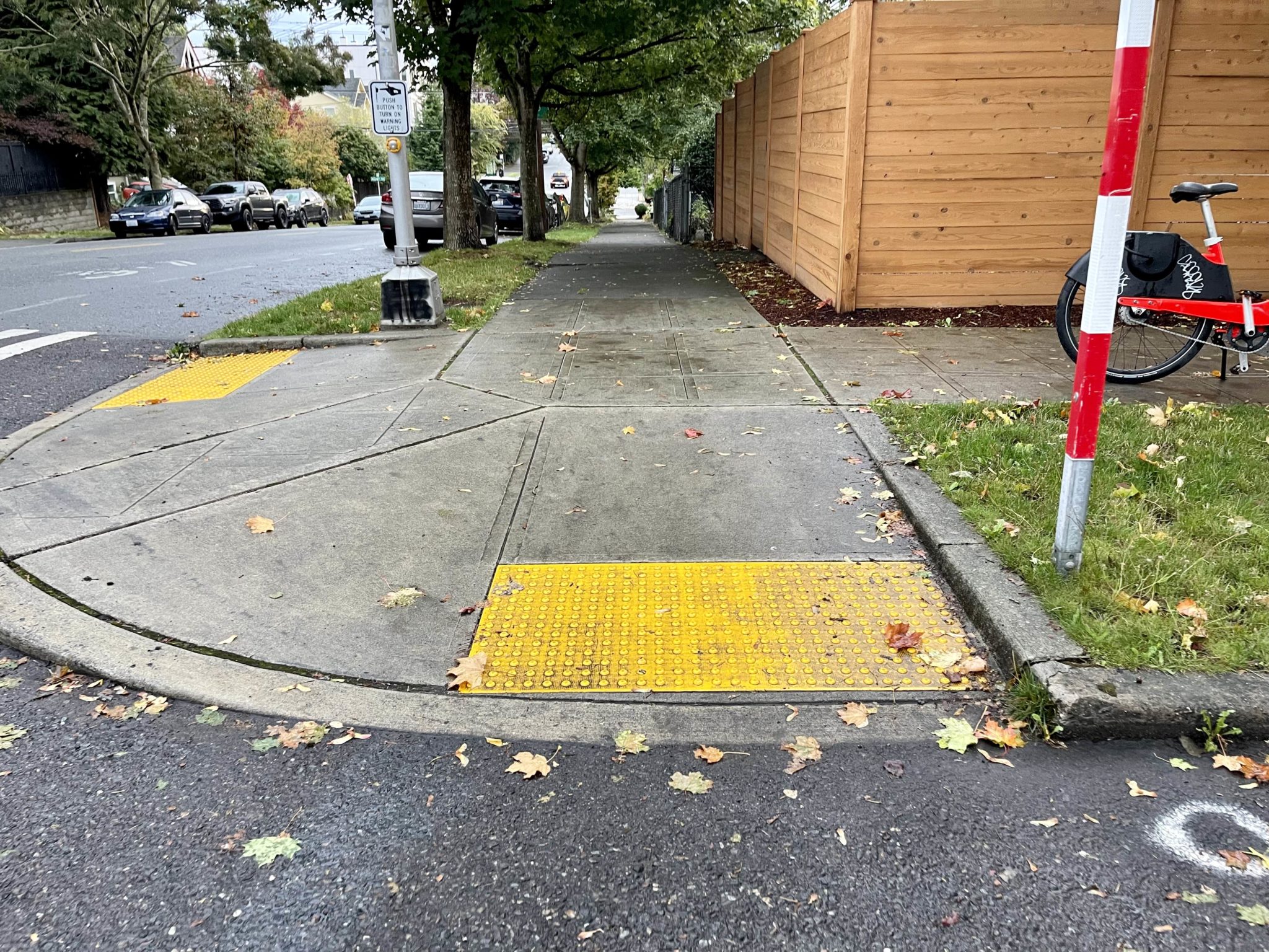 Photo of a sidewalk curb ramp in Seattle. The curb ramp is in the middle of the photo, with the street visible in the foreground and sidewalk visible above it.