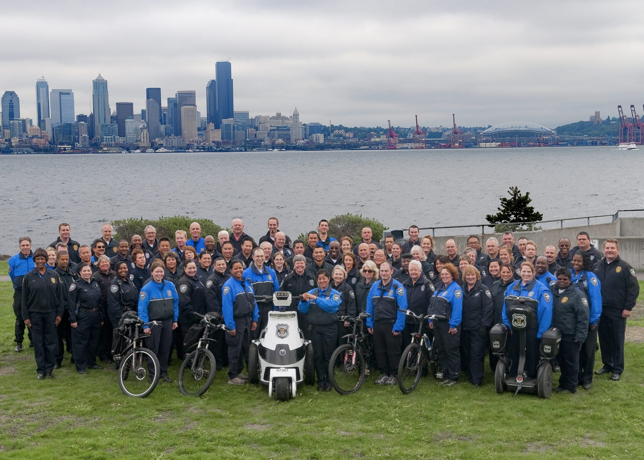 The Seattle Parking Enforcement team poses for a group photo in 2019, with the downtown Seattle skyline visible in the background.