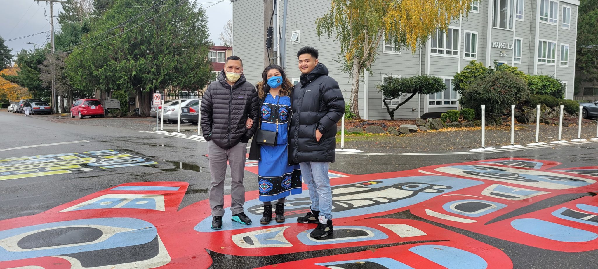 Artist Romel Belleza stands with his proud parents stand on top of the new mural in the Little Brook neighborhood of Lake City Way.