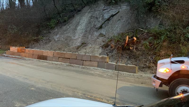 Photo of concrete ecology blocks that help create a barrier where the landslide occurred on Tuesday, January 11, along Highland Park Way SW in West Seattle. The street is visible in the foreground, as the concrete blocks and hillside are visible up the upper middle part of the image.
