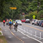 People bike in the new protected bike lanes on streets around Green Lake, which were completed in summer 2021.