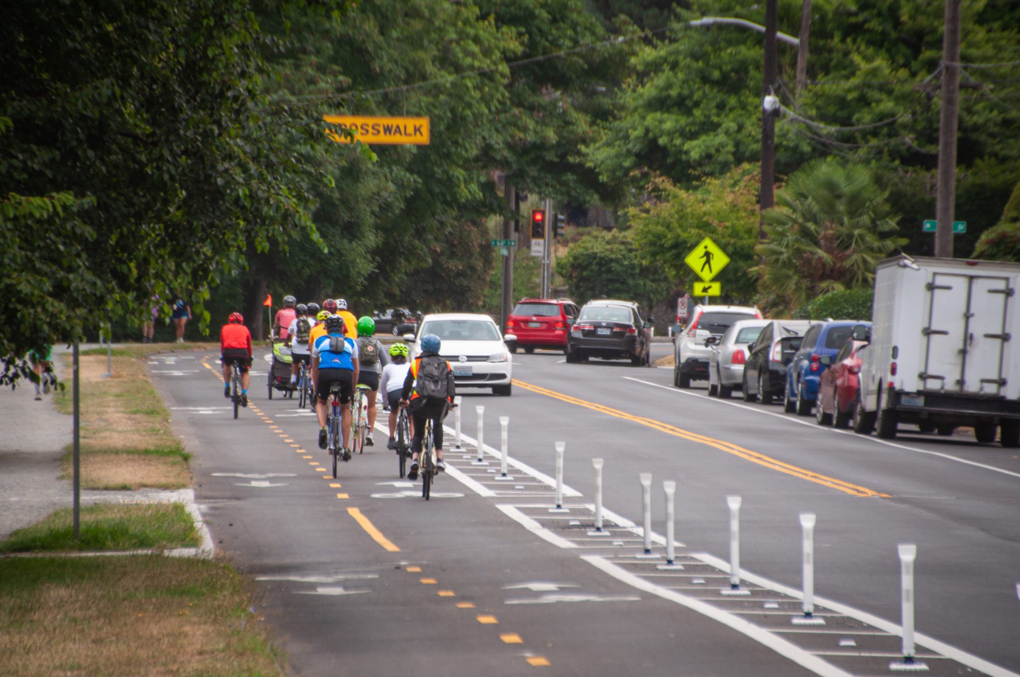 People bike in the new protected bike lanes on streets around Green Lake, which were completed in summer 2021.