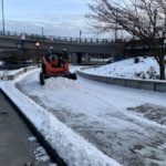 Our worker operates a grader (a type of snowplow) along the S Royal Brougham Way pedestrian walkway near T-Mobile Park.