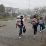 Several students cross the street in a Seattle neighborhood while walking to school.