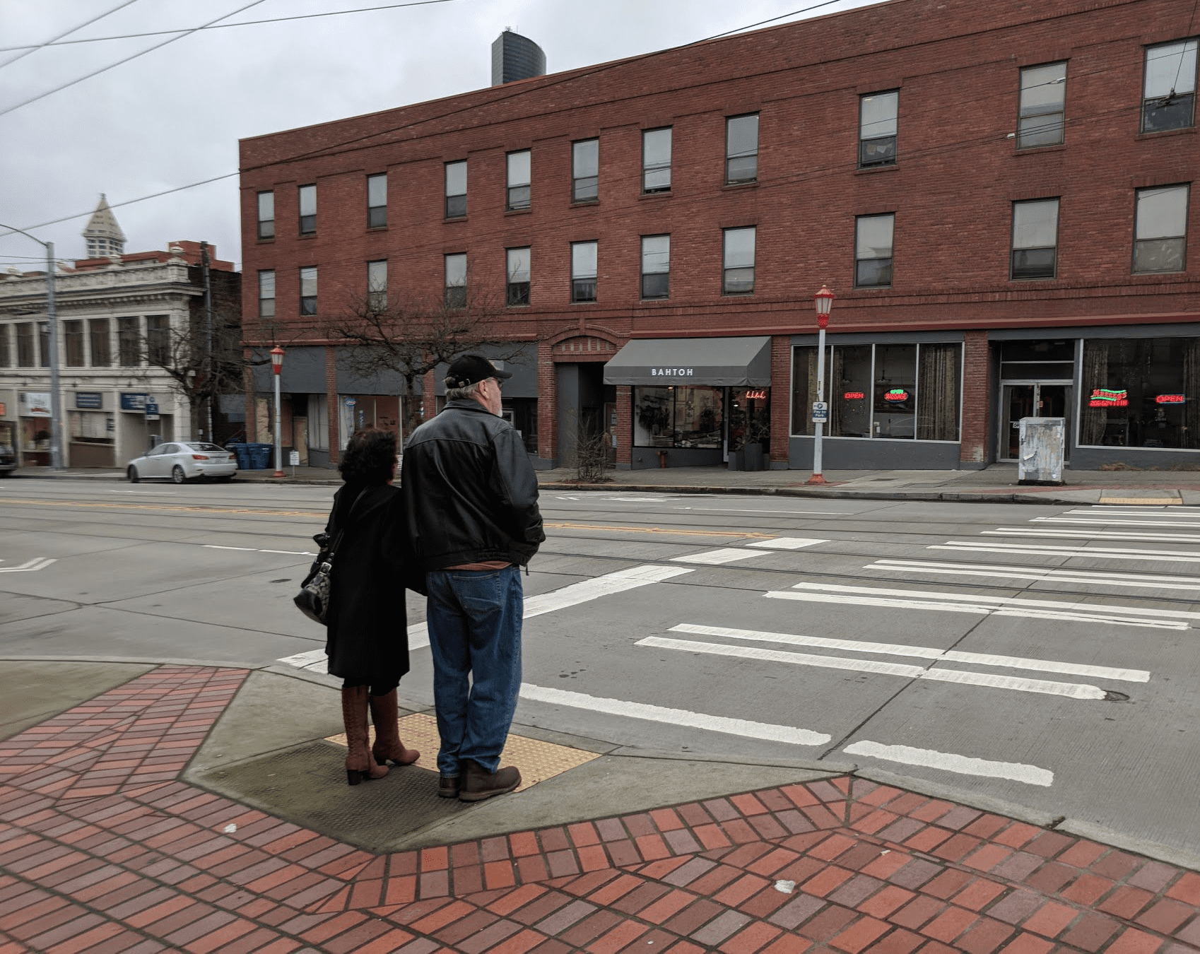 Two people wait to cross the street at a signed crosswalk in Seattle’s Chinatown-International District.