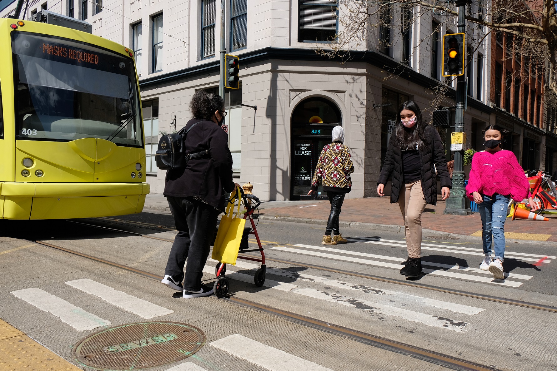 People walk across the street in Seattle’s Pioneer Square neighborhood. The Seattle Streetcar is visible to the left.