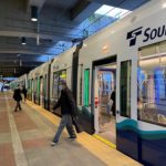 People get on and off an existing Sound Transit light rail train in Seattle.