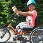 A young rider smiles while riding an adaptive cycle in Seattle.