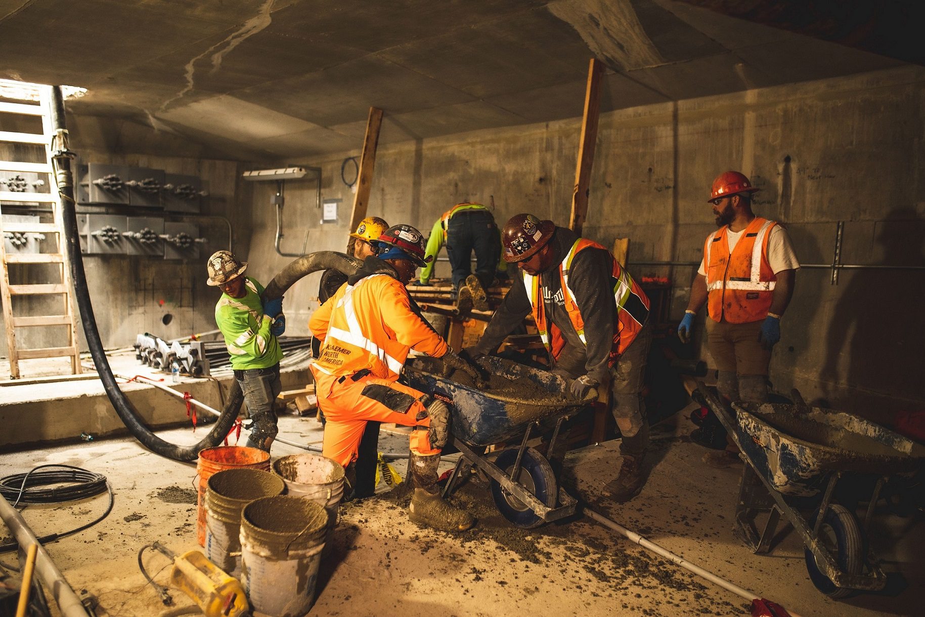 People work inside the West Seattle Bridge to pour structural concrete. Several workers wear personal protective equipment and work to install the concrete.