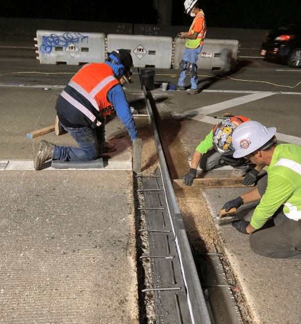 Crews work on I-5 expansion joints during a recent weekend. Several construction workers crouch to work on the bridge expansion joints, in a section of the freeway closed to traffic.