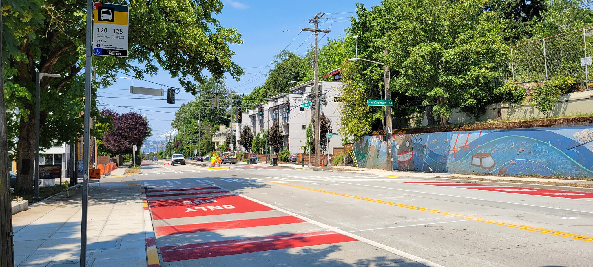 Example of a bus-only lane on Delridge Way SW. The bus-only lane is painted red, with trees and traffic signs shown in the background.