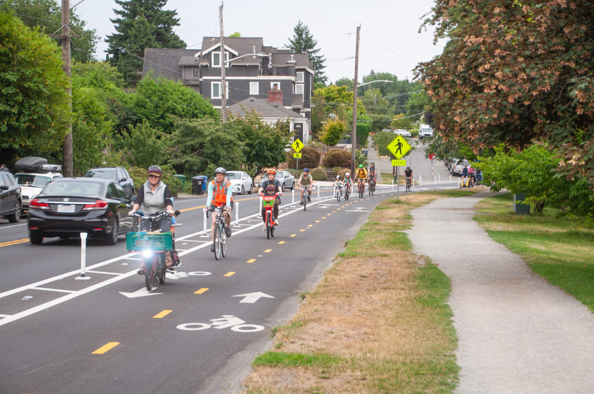 A group of nine cyclists riding bikes around Green Lake’s protected bike lane during the day