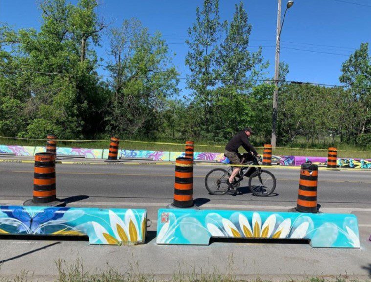 Concrete Guards, decorated with public art, providing separation for the bike lane and the vehicle travel lane.